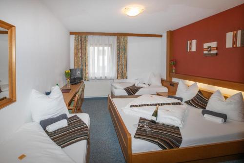 a hotel room with three beds and a desk at Hotel Untermetzger in Zell am Ziller