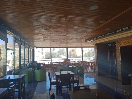 a dining room with tables and chairs and windows at Petra Visitors Apartments in Wadi Musa