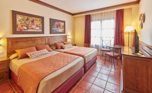 Dormitorio con cama, escritorio y TV en PortAventura Hotel El Paso - Includes PortAventura Park Tickets en Salou