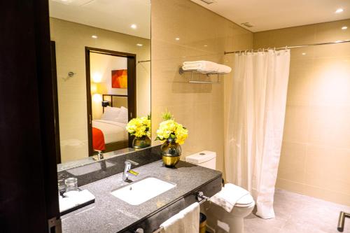 een badkamer met een wastafel, een toilet en een spiegel bij Hotel Lucky Chinatown in Manilla
