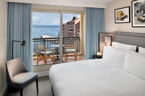 a bedroom with a bed and a view of the ocean at Columbus Hotel Monte-Carlo, Curio Collection by Hilton in Monte Carlo