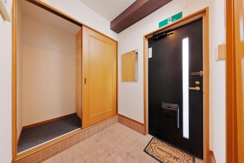 a hallway with a black door and a tile floor at Terrace Terano#101 in Tokyo