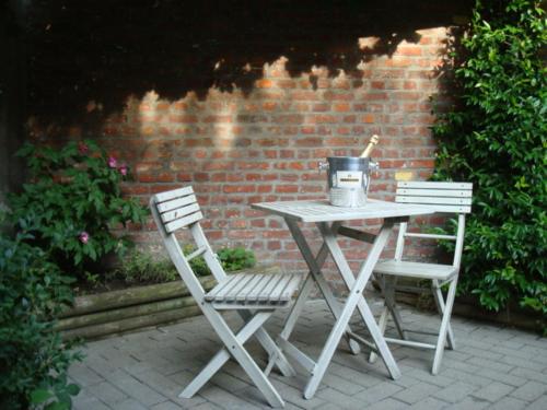 dwa krzesła i stół z garnkiem w obiekcie LE CHAT NOIR w mieście Ypres