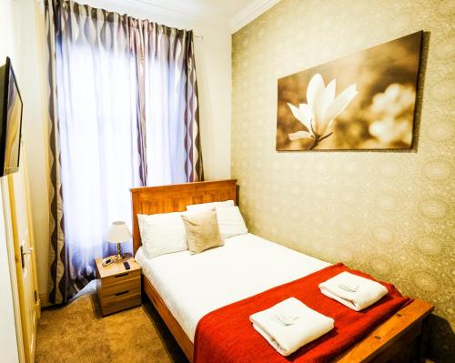 - une chambre avec un lit blanc et une couverture rouge dans l'établissement Balmore Guest House, à Édimbourg