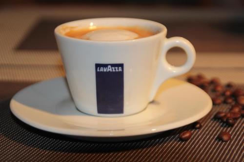 a cup of coffee on a plate with coffee beans at Cafe Hotel Rudzons in Madona