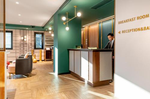 a man standing at a counter in a hospital lobby at Hotel Canada in Milan