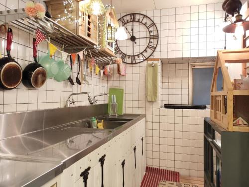 a kitchen with a sink and a tiled wall at Dyeing and Hostel Nakashimaya - Female Only in Kumamoto
