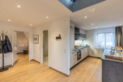 a kitchen with white cabinets and a wooden floor at RH-Appartements 15 Minuten von Basel im Dorf Rührberg in Grenzach-Wyhlen