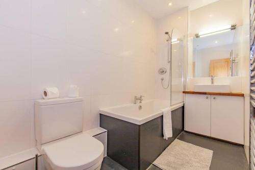 a white bathroom with a toilet and a sink at Unique and quirky central apartment with parking in Oxford