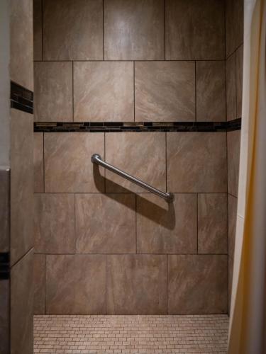 a shower with a brown tiled wall and a towel rack at Parkside Inn in Long Beach