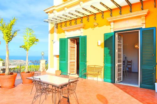 a patio with a table and chairs on a building at Villa La Timpa - antica e maestosa villa con jacuzzi privata con una meravigliosa vista sull'Etna e sul mare in Acireale