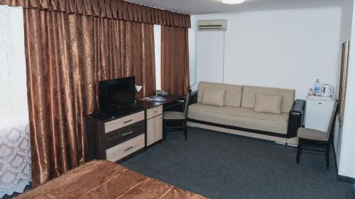 a room with a bed and a desk with a television at Aktobe Hotel in Aktobe