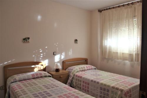 a bedroom with two beds and a window at Apartaments Lamoga - Monteixo in Torredembarra