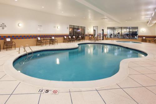 a pool in a hotel lobby with tables and chairs at Holiday Inn Express & Suites Zanesville North by IHG in Zanesville