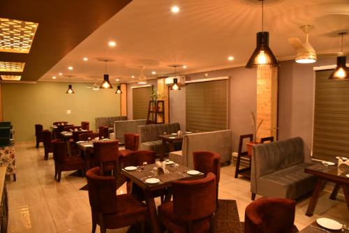 a dining room with tables and chairs and lights at Mastiff Hotel, Gopalpur in Pālampur