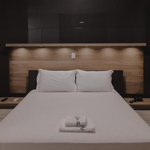 Una cama blanca con una toalla encima. en Petri Plaza Hotel, en Francisco Beltrão