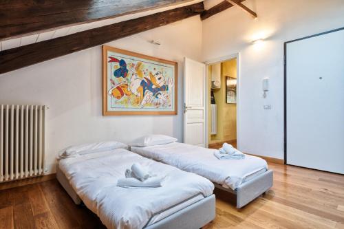 two beds in a room with a painting on the wall at Turin CityView Stylish Loft in Turin