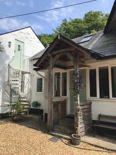 a small white house with a wooden pergola at Vinegar Hill Pottery in Lymington
