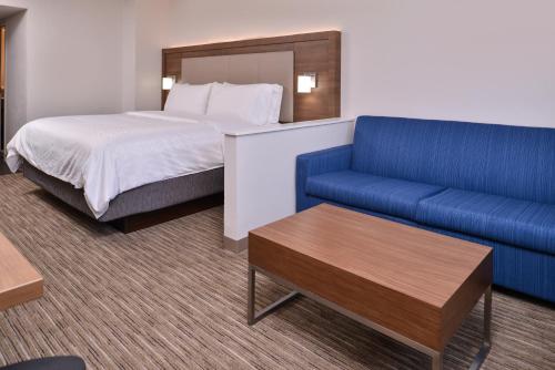 a hotel room with a bed and a blue couch at Holiday Inn Express Hotel and Suites Mesquite by IHG in Mesquite
