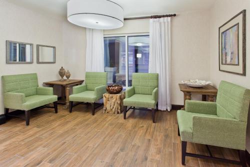 a living room with green chairs and a table at Holiday Inn Express Hotel & Suites Huntsville West - Research Park, an IHG Hotel in Huntsville