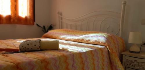 a bed with a comforter and a hat on top of it at Il Girasole in SantʼAntìoco
