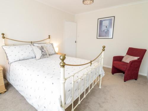 a bedroom with a white bed and a red chair at Castle Cove in Abergele