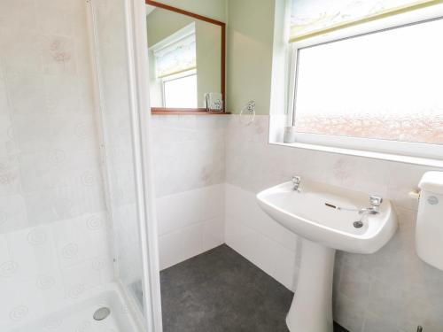 a white bathroom with a sink and a shower at Castle Cove in Abergele