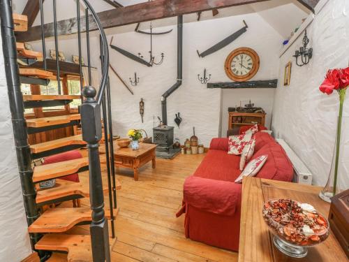 a living room with a red couch and a table at Heather Cottage in Milford Haven