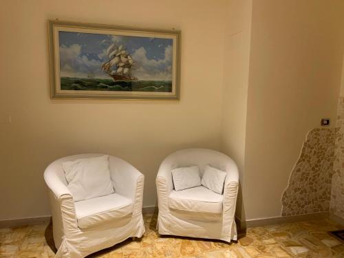 two white chairs in a room with a painting at Maison Belle Vue in Chioggia