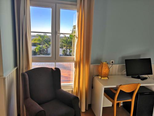 a room with a desk and a chair and a window at Hotel Marisma Sancti Petri in Chiclana de la Frontera