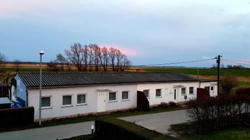 a white building with a black roof on a street at Ferienwohnung Thees in Ummanz