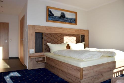 Schlafzimmer mit einem großen Bett mit einem Kopfteil aus Holz in der Unterkunft Ferienhotel Wolfsmühle in Rodishain