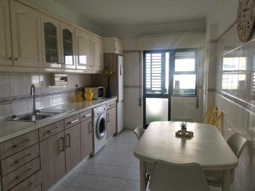 a kitchen with a table and a sink and a dishwasher at Penha House in Faro