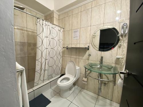 y baño con aseo, espejo y lavamanos. en Apartahotel Guaraguao en San Pedro de Macorís