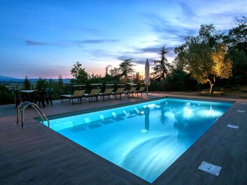 een zwembad met stoelen en een tafel en een zonsondergang bij Belvilla by OYO Villa il Castello in Castiglion Fiorentino
