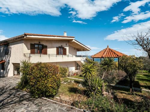 een huis met een veranda en een dak bij Holiday villa with sea view in Paralia Avlidas in Dhílesi