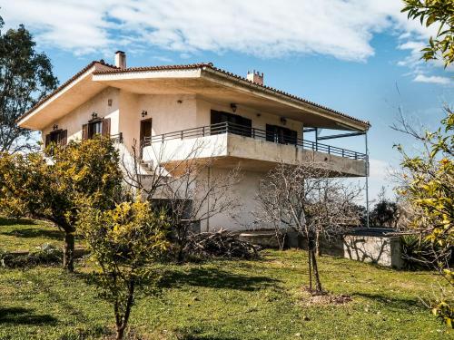 a house on a hill with trees in front of it at Holiday villa with sea view in Paralia Avlidas in Dhílesi