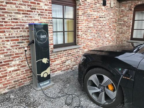 a car is hooked up to an electric meter next to a brick wall at B&B Ter Gracht in Wevelgem