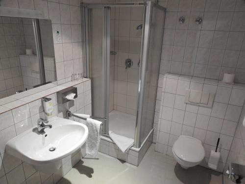 a bathroom with a toilet, sink, and bathtub at Hotel Anhalt in Köthen