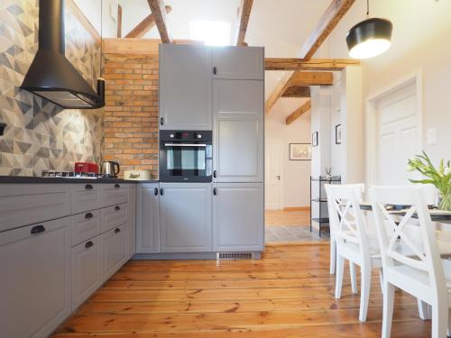 a kitchen with white cabinets and a table and chairs at Berni's home Apartament z tarasem in Sopot