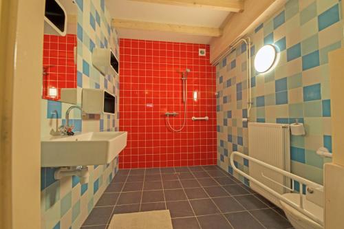 y baño con lavabo, ducha y azulejos rojos. en Gastopstal en Wyns