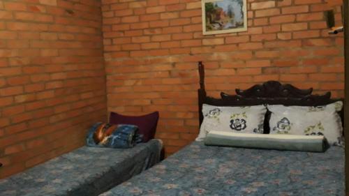 a bedroom with two beds and a brick wall at Aconchego Caminho das Cachoeiras in Rio Acima