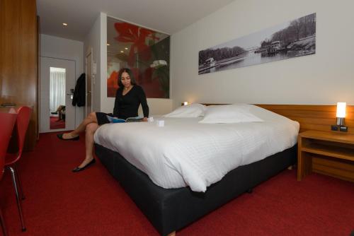 a woman sitting on a bed in a hotel room at Corbie Mol in Mol