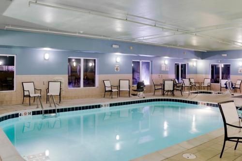a pool in a hotel with chairs and tables at Holiday Inn Express & Suites Jacksonville, an IHG Hotel in South Jacksonville