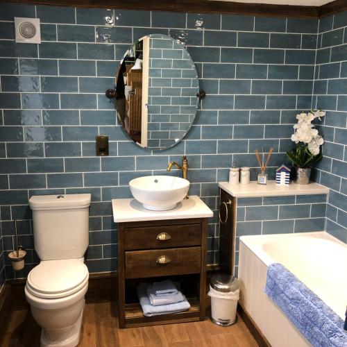 a bathroom with a toilet and a sink and a mirror at Coldharbour Cottage with Hot Tub in Stone