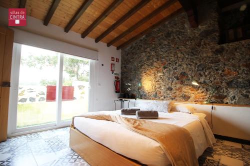 sypialnia z dużym łóżkiem i kamienną ścianą w obiekcie Villas de Cintra w mieście Sintra