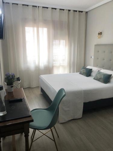 a bedroom with a bed and a desk and a chair at Hotel Marqués de Santillana in Torrelavega