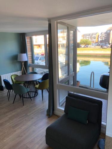 - un salon avec une table, des chaises et une grande fenêtre dans l'établissement Grande Marina Vue Port, à Deauville