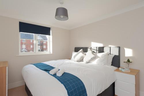 Schlafzimmer mit einem Bett mit weißer Bettwäsche und einem Fenster in der Unterkunft Treeview Apartment- A lovely 2 bed apartment near Colchester North Station by Catchpole Stays in Colchester