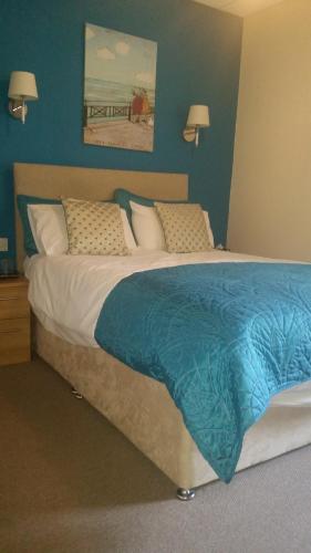 a bed in a room with a blue wall at Le Maitre in Southport